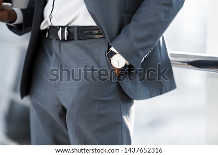Fashion and Punctuality Concept. Man Hand with Wrist Watch in the Pocket of Stylish Pants