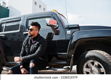 Fashion Rich Beard Arab Man Wear On Black Jeans Jacket And Sunglasses Posed Against Big Black Suv Car. Stylish, Succesful And Fashionable Arabian Model Guy.