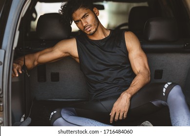 Fashion Shoot Of A Handsome And Sexy Indian Or Arab Looking Male Fitness Model With A Gym Fit Body And Black Curly Hair And A Stylish Small Beard Sitting And Posing In The Back Of A Car