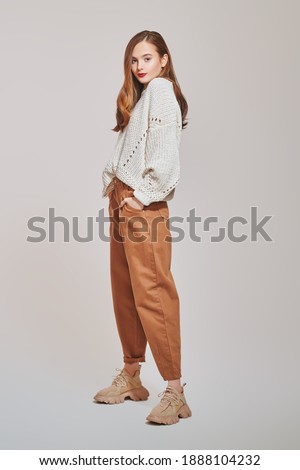 Fashion shot. Beautiful young girl in modern casual clothes posing at studio. Full length portrait.  