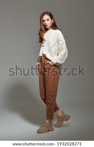 Fashion shot. Beautiful young girl in modern casual clothes posing at studio in motion. Full length portrait.  