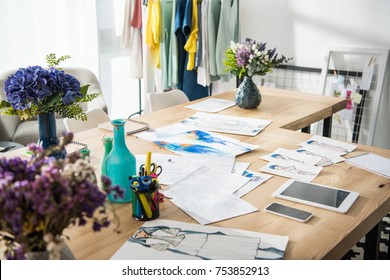 Fashion Sketches And Digital Devices On Table In Clothing Design Studio