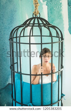 fashion slave in captivity of beauty. prisoner woman in cage - home confinement. freedom of cute girl in cage chair. modern furniture design and home comfort. justiceand crime. woman in iron cage.