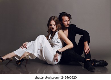 Fashion studio photo of sexy young coupl of brown-haired woman and brunette man dressed in black and white suits like yin-yang and sitting on the flor,love,lovers,Valentines day