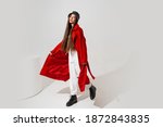 Fashion studio photo of stylish european brunette woman in red coat and black hat posing on white background.  Trendy winter accsesorises. Full lenght. 