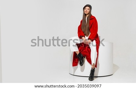 Fashion studio photo of stylish european brunette woman in red coat and black hat posing on white background.  Trendy winter accsesorises.