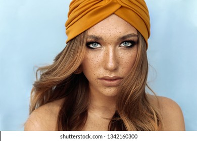 fashion studio portrait of beautiful young woman with brown hair and freckles face