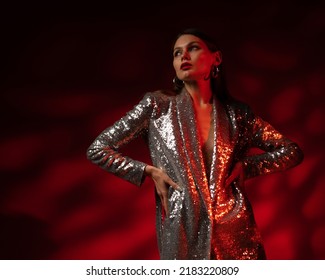 Fashion studio portrait of confident woman with wearing trendy sequin blazer dress, posing in darkness with red light. Copy, epmty space for text
