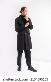 Fashion and style, full body young pretty man in black long coat posing in studio