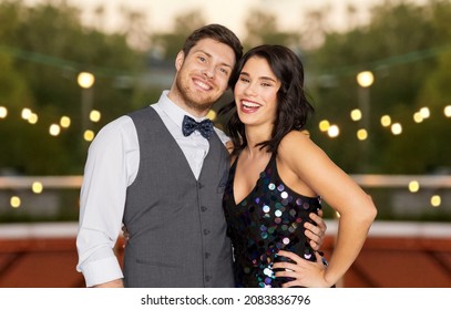 Fashion, Style And Holidays Concept - Happy Couple Hugging At Rooftop Party Over Lights Background