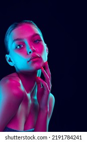 Fashion  style  Young beautiful girl and well  kept skin   without makeup isolated over dark background in neon light  Concept natural beauty  art  emotions  cosmetics   youth