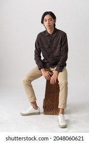 Fashion And Style , Young Man Wearing Brown Shirt With Khaki Pants Sitting Chair In Studio