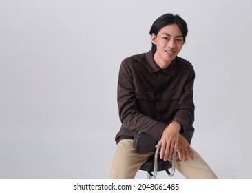 Fashion And Style , Young Man Wearing Brown Shirt With Khaki Pants Sitting Chair In Studio