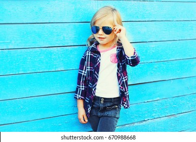 Fashion stylish child wearing a sunglasses and checkered shirt on a blue background, profile view - Powered by Shutterstock