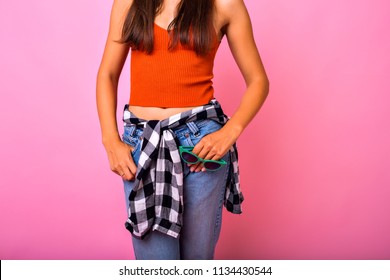 Fashion Stylish Details, Young Slim Woman Wearing Trendy Denim Jeans Crop Top And Plated Shirt, Holding Vintage Cat Eye Sunglasses, 90s Hipster Style, Pink Studio Background.