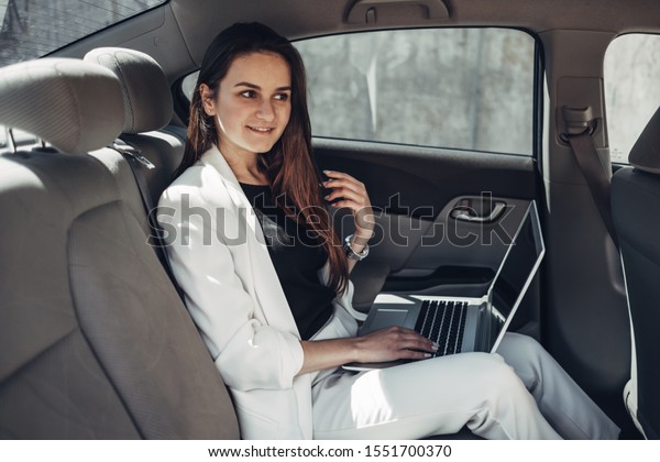 Fashion\
Stylish Girl in White Suit Works at Laptop in\
Car