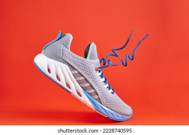 Fashion stylish sneakers with flying laces. Running sports shoes on orange background. Stability and cushion running shoes.