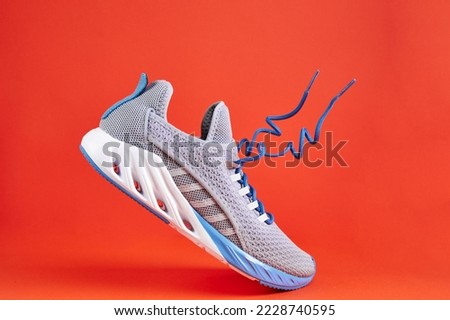 Fashion stylish sneakers with flying laces. Running sports shoes on orange background. Stability and cushion running shoes.