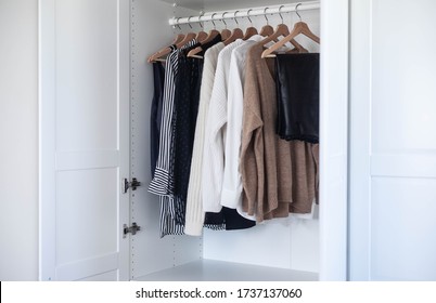 Fashion stylist clothes basic wardrobe.Neutral colors: white, black, beige. White closet, wooden hanger shoulders. - Shutterstock ID 1737137060
