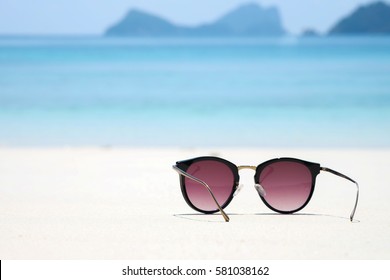 Fashion sunglasses on sea beach with clear blue sky. Summer holiday relax background with copy space.
