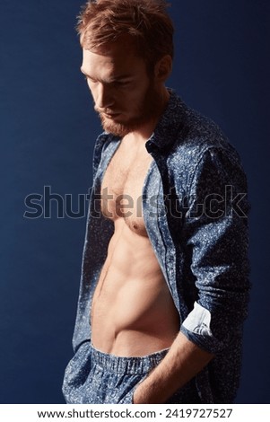 Fashion, thinking or model with abs in studio on a blue background wearing an open unbuttoned shirt. Ginger man, body or handsome male person posing on color wall for masculine style with six pack Foto d'archivio © 