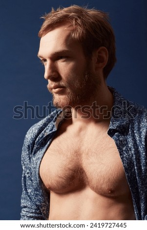 Fashion, thinking or model with chest in studio on a blue background wearing an open unbuttoned shirt. Ginger, body or handsome male person posing on color wall for masculine style, health or fitness Foto d'archivio © 