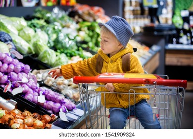 Fashion toddler boy with backpack, shopping in supermarket shop