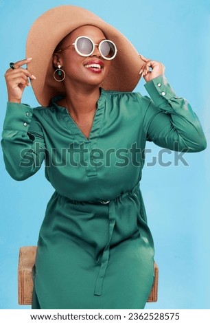 Fashion, travel and black woman with sunglasses for cool style summer isolated in a studio blue background. African, hat and young person relax with clothes for glamour or luxury accessories