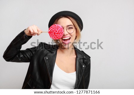 Fashion woman having fun with lollipop over grey background