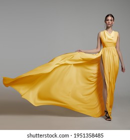 Fashion Woman In Long Silk Yellow Dress. Gray Background