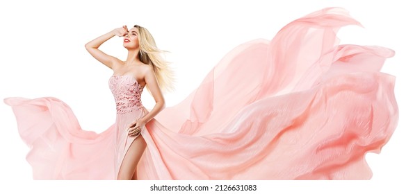 Fashion Woman In Pink Silk Dress Flying Over White. Happy Blonde Model With Long Wavy Windy Hair Style In Chiffon Gown Over Isolated Studio Background