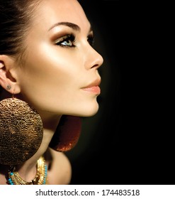 Fashion Woman Profile Portrait isolated on black. Golden Jewels. Trendy Makeup. Smoky eyes make up. Gold Jewellery. Accessories 