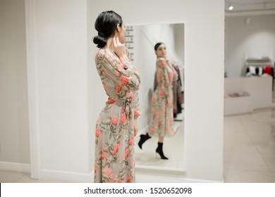 Fashion woman in a shop looking at clothes. Trying on a dress in front of a mirror. Shopping center