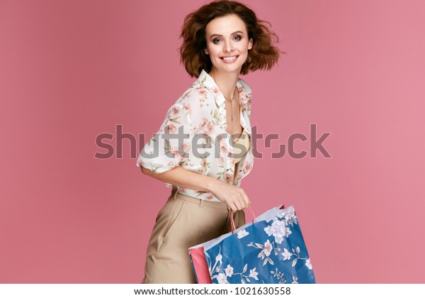 ファッション ピンクの背景におしゃれな服で買い物袋を持つ女性 カラフルな紙袋を持つスタイリッシュな服を着た 幸せな笑顔の若い女性モデル 女性スタイル 高品質画像 の写真素材 今すぐ編集