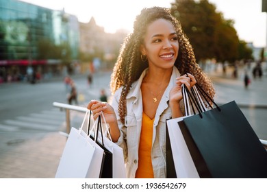 Fashion woman with shopping bags walking on street. Spring Style. Consumerism, sale, purchases, shopping, lifestyle concept. - Shutterstock ID 1936542679