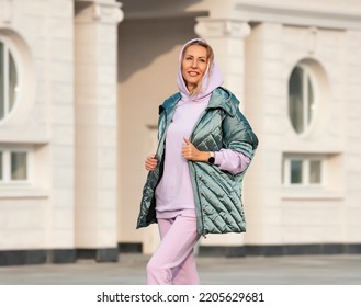 Fashion women clothes. A woman in a warm oversized vest and a lilac hooded sweatshirt. Elegant comfortable clothing for sports and walks.