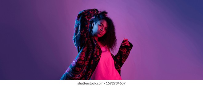 Fashion young african girl black woman wear stylish jacket dancing looking at camera isolated on party purple disco studio background, horizontal banner for website design, portrait, copy space