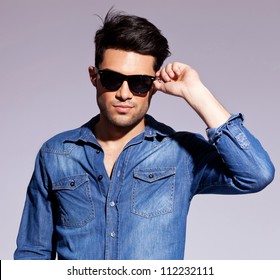 Fashion Young Man Holding His Fashionable Sunglasses On Gray Background
