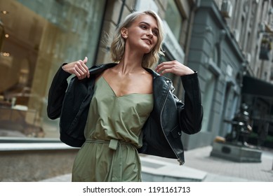 Fashion. Young stylish woman walking on the city street taking off jeans jacket smiling joyful close-up