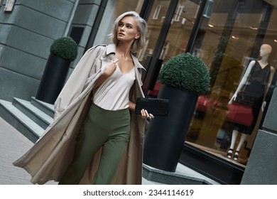 Fashion. Young stylish woman walking on the city street looking aside curious