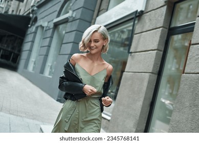 Fashion. Young stylish woman walking on the city street looking down laughing playful