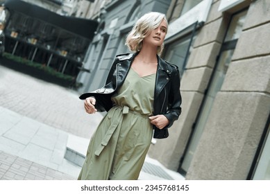 Fashion. Young stylish woman walking on the city street looking aside smiling curious