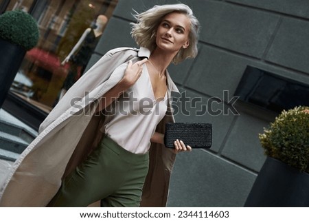 Fashion. Young stylish woman walking on the city street looking aside smiling happy close-up