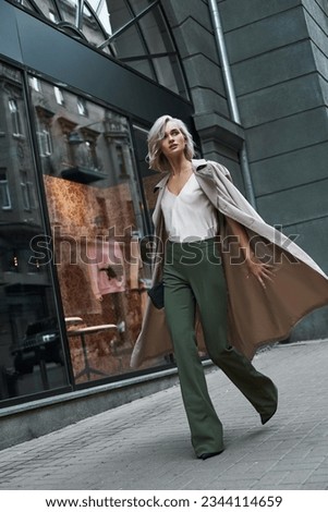 Fashion. Young stylish woman walking on the city street looking aside curious full body shot