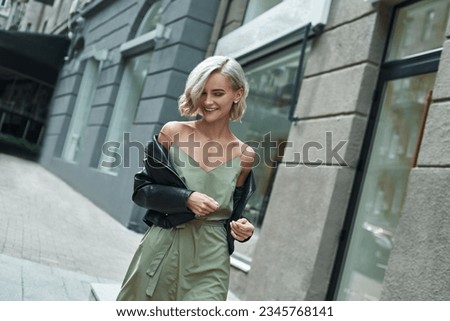 Fashion. Young stylish woman walking on the city street looking down laughing playful