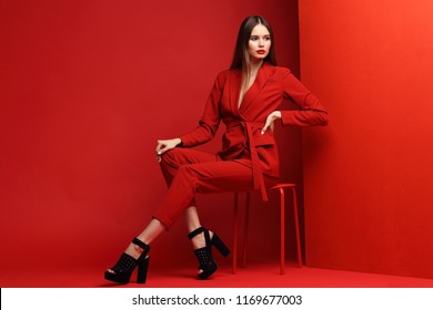 Fashion Young Woman In Red Suit. Red Background.