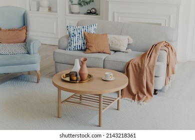 Fashionable Apartment Interior. Soft Pillows On Couch And Armchair. Lovely Decoration With Pots And Vases On Shelves. Table Near Sofa. Rug On Floor. Sweet Room, Lounge And Cozy Home Textile Concept.