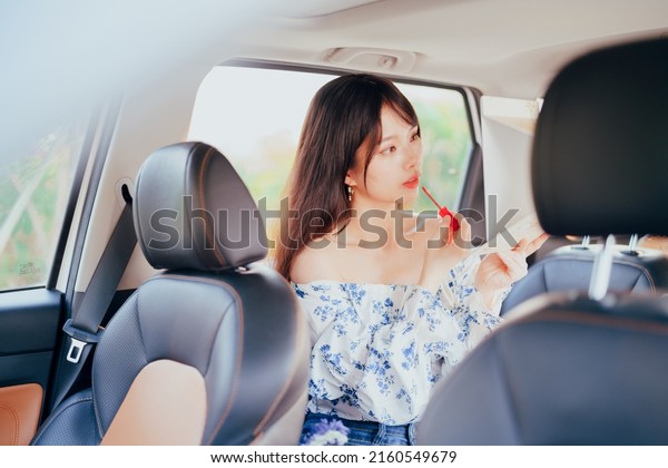Fashionable Asian girls\
make up in the car