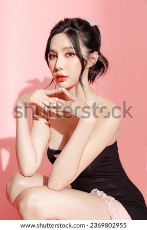 Fashionable Asian woman have good figure and clear fresh skin in black trendy dress pose on isolated pink background. Plastic Surgery, Concept of beauty, body and skin care, health, spa, cosmetics.