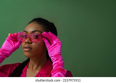 Fashionable Beautiful Black Woman Wearing Trendy Pink Sunglasses, Fuchsia Color Blouse, Gloves Posing On Green Background. Close Up Studio Portrait. Copy, Empty Space For Text